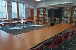 conference room with long tables, chairs and a monitor